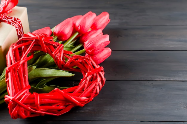 Hart van rieten geplaatst, geschenkdoos en tulpen op een houten bord