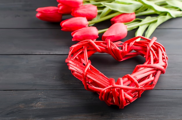 Hart van rieten geplaatst, geschenkdoos en tulpen op een houten bord