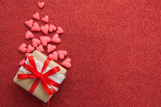 Harten en geschenkdoos op een rode glitter oppervlak. Plat lag met kopie ruimte voor Valentijnsdag groet