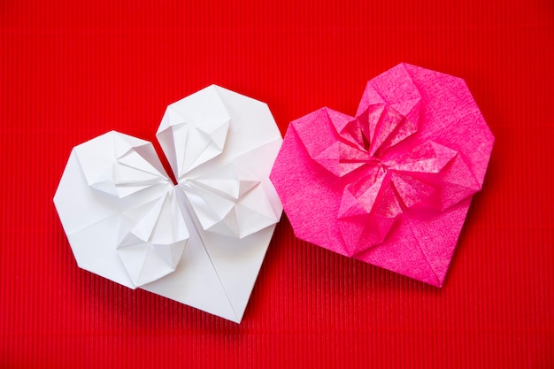 Harten gemaakt van papieren origami op rode kartonnen achtergrond voor Valentijnsdag