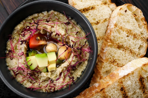 Hartige hummus met avocado en tomaten op een zwarte plaat