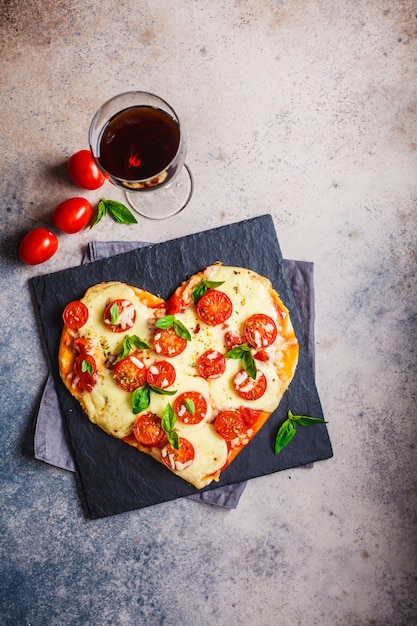 Hartpizza met mozarella en tomaten op lei met wijn