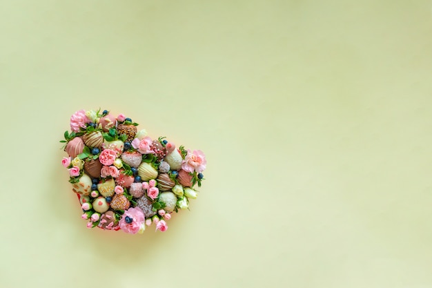 Hartvormige doos met handgemaakte aardbei in chocolade en bloemen als een geschenk op Valentijnsdag op groene achtergrond met vrije ruimte voor tekst