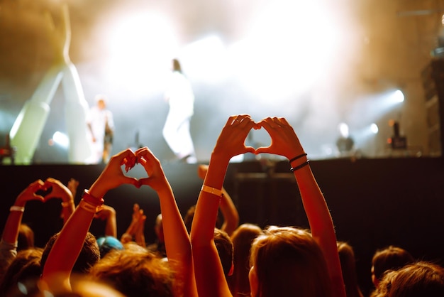 Foto hartvormige handen bij concert liefhebbende artiest en festival muziekconcert met verlichting tijdens het concert