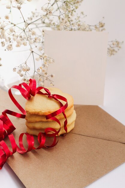 hartvormige koekjes met een rood lint en een wit boeket bloemen.