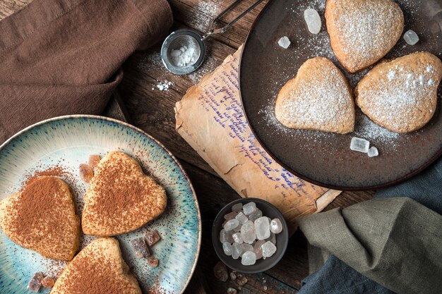 Hartvormige koekjes worden bestrooid met cacao en poedersuiker op een vintage achtergrond.