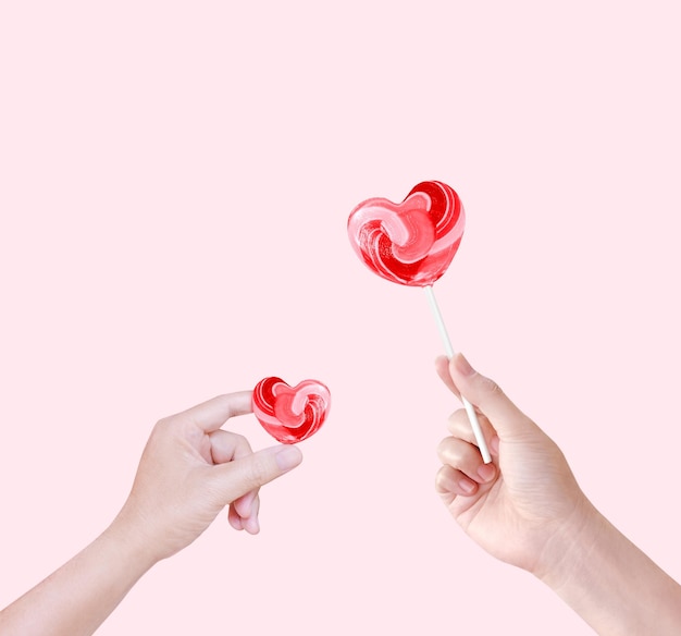 Foto hartvormige lolly snoep in de hand geïsoleerd op roze achtergrond