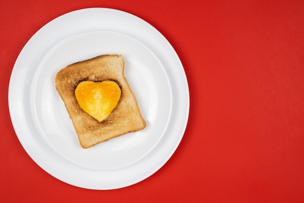 Hartvormige ontbijtsandwich met ei in het midden op een bord.