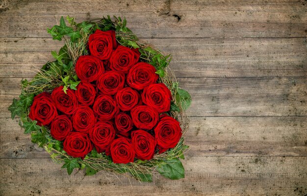 Foto hartvormige rode rozen boeket op rustieke houten achtergrond. valentijnsdag concept. getinte foto in retrostijl