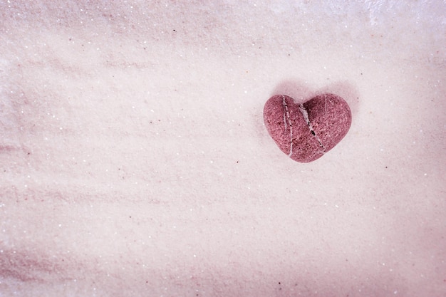 Hartvormige steen Pebble of Heart op zand dat glinstert in de zon Geweldige vondst op het strand Liefdesconcept