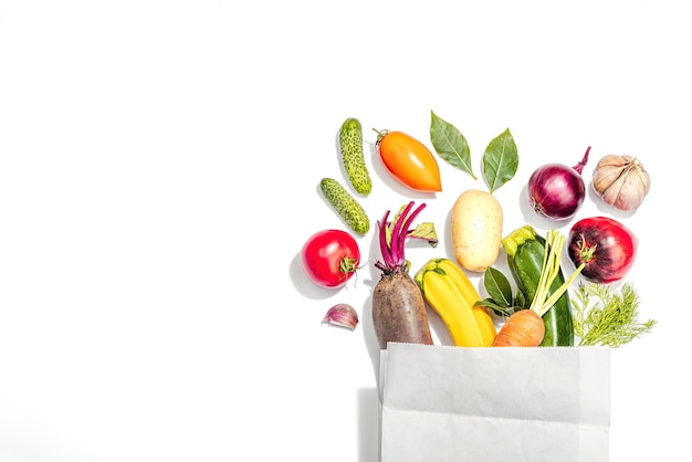 Harvest of autumn vegetables isolated on white background Urban farm produce shopping in a paper bag hard light dark shadow flat lay top view