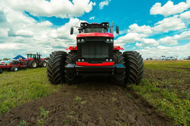 Campo di raccolta con trattore rosso modi campo di erba secca dopo il raccolto raccolta nei campi stoccarsi di fieno per l'inverno arare un campo con un trattore rojo coltivazione