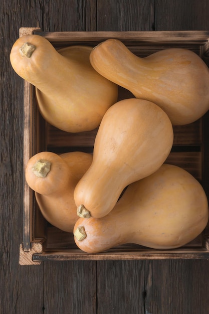 Harvest pumpkins on a wooden table in a box, top view