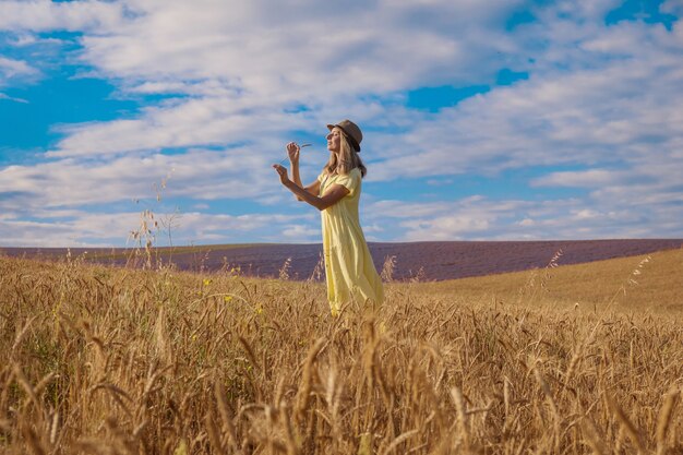 Il grano maturo del raccolto cresce nel campo il grano dorato e la ragazza sta camminando attraverso il campo...