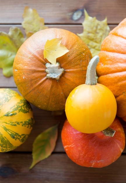 収穫、季節、広告、秋のコンセプト – 自宅の木製テーブルの上にカボチャと葉をクローズアップ
