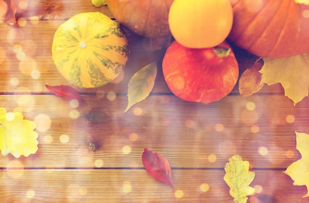 収穫、季節、広告、秋のコンセプト – 自宅の木製テーブルの上にカボチャと葉をクローズアップ