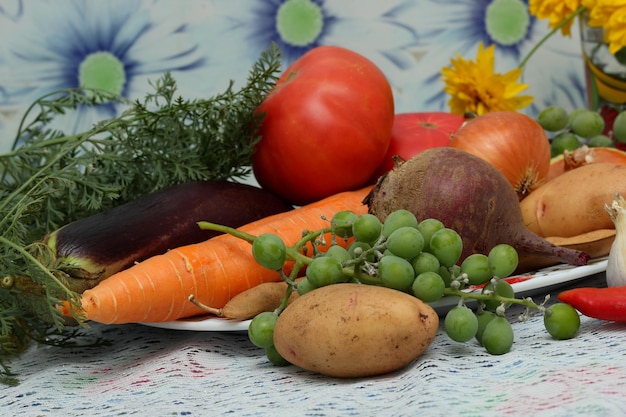 Harvest vegetables and fruits on a white plate on the table on a blue background Healthy organic food close up Vegan day concept