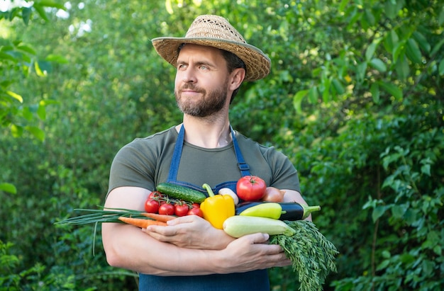 Harvester in strohoed houdt verse rijpe groenten vast