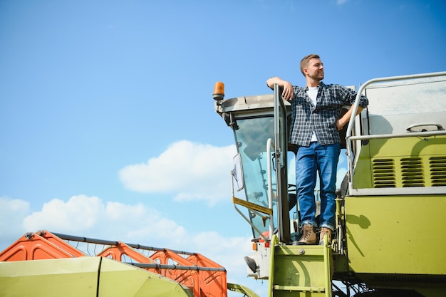 Photo harvester machine driver climbing into a cab to harvest his wheat field farmer getting in combine on ladder holding railing agronomist rancher after harvesting work