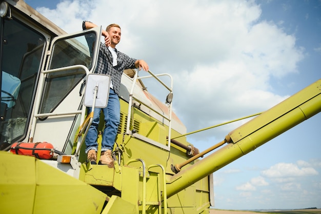 Harvester machine driver climbing into a cab to harvest his wheat field Farmer getting in combine on ladder holding railing Agronomist Rancher after harvesting work