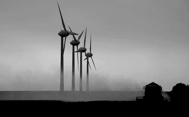 Foto harvester op het veld naast windturbine schot tegen de zon