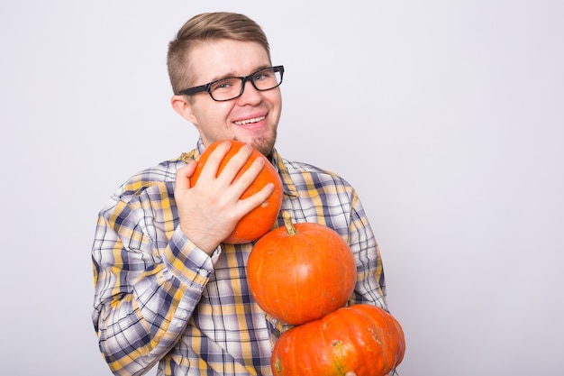 Raccolta di halloween e concetto di persone uomo con occhiali neri che tengono tre zucche su bianco