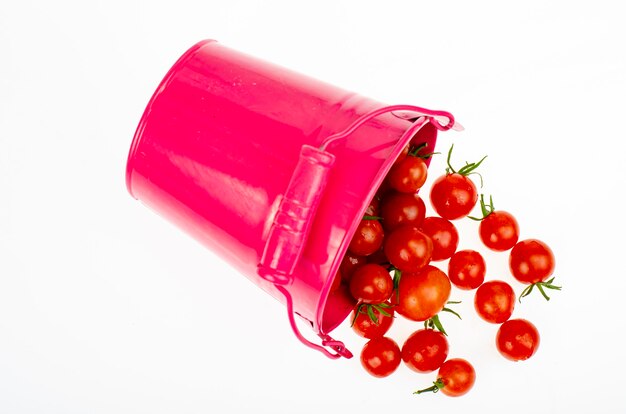 Harvesting. Red ripe tomatoes in colored buckets on white background. Studio Photo.