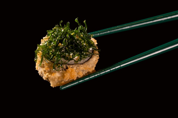 Hashi hold sushi and rolls isolated over black background