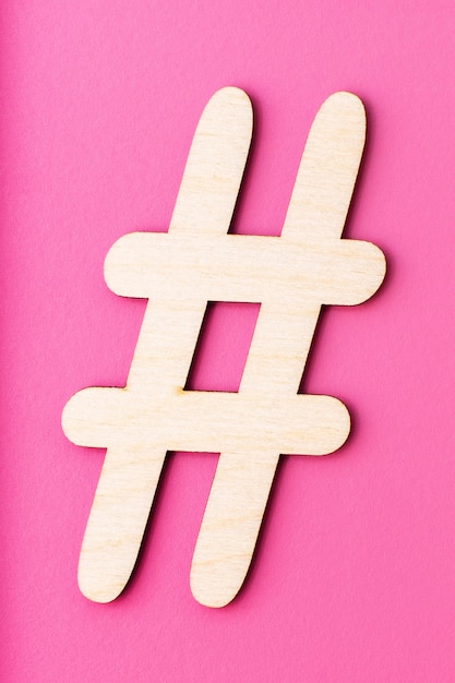 Hashtag teken gemaakt van houten materiaal op roze achtergrond