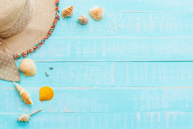 Hat beach and shells on blue wooden background for summer concept.