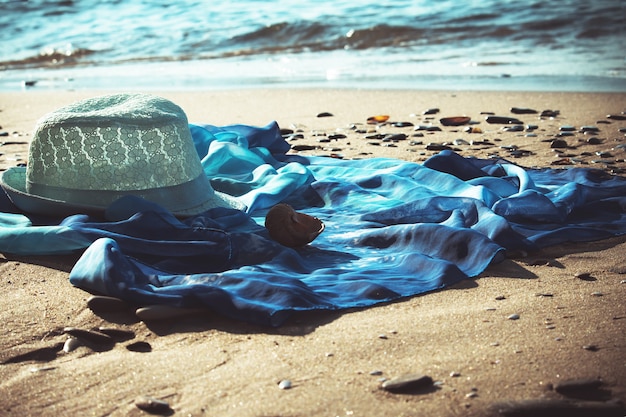 Hat and beach tunic on the beach with the seashore