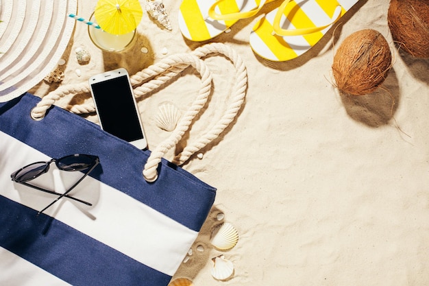 Hat strandtas zonnebril en glas kokoswater op een tropisch strand