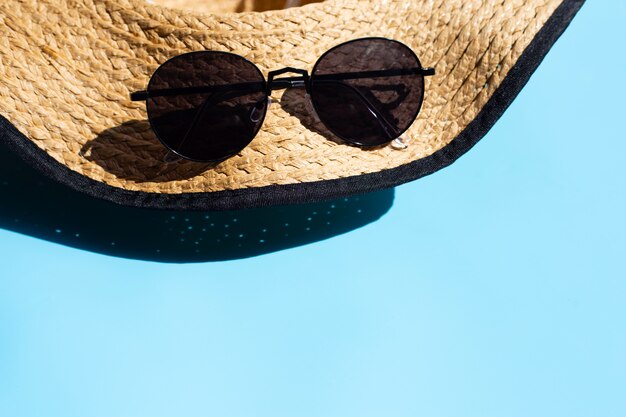 Cappello e occhiali da sole su sfondo blu. goditi il concetto di vacanze estive.