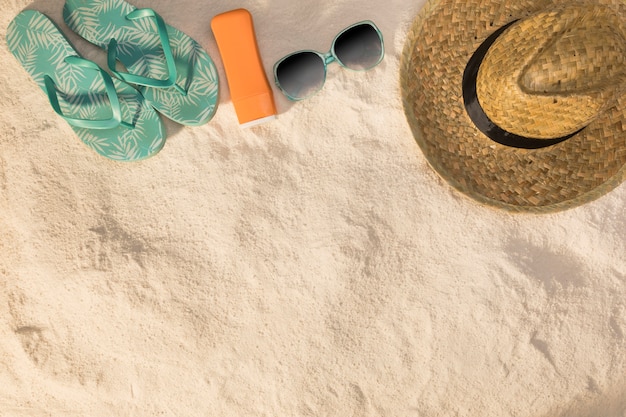 Фото Шляпа солнцезащитные очки синие сандалии и солнцезащитный крем на песке