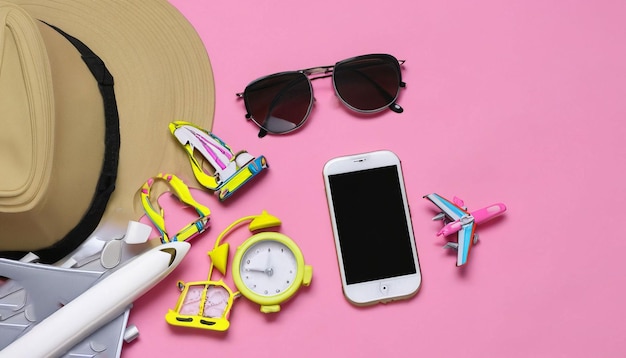 A hat, sunglasses, a phone, and a hat are on a pink background.