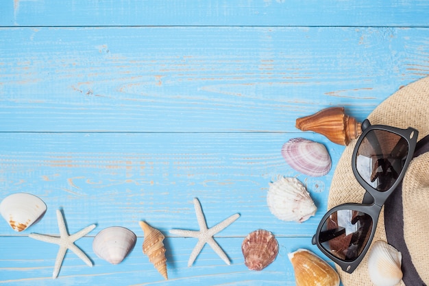 hat, sunglasses and shell on blue 