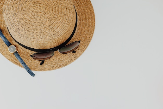 Cappello, occhiali da sole e un orologio su sfondo bianco