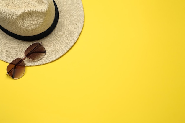 Hat and sunglasses on yellow background flat lay with space for text Sun protection