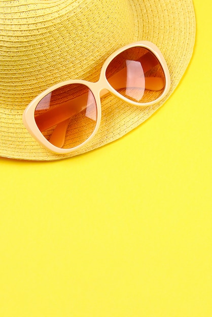 Cappello, occhiali da sole su uno sfondo giallo.