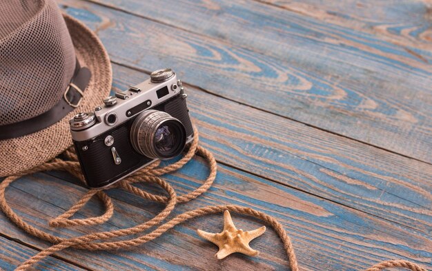 Foto cappello corda per telecamera vintage e stella di mare su tavolo di legno blu concetto di viaggio posto per il testo