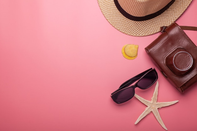 Hat, vintage camera, sunglasses, starfish, shell isolated on pink