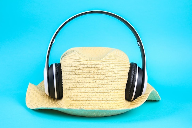 青い背景の上の白いワイヤレスヘッドフォンの帽子休息のリラクゼーションの概念