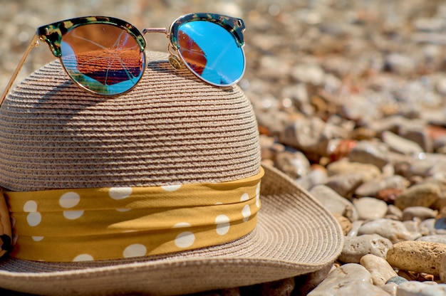 Hat with sunglasses on a pebble beach