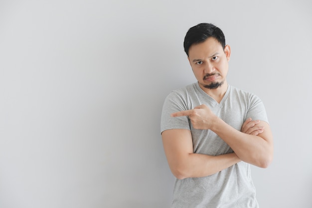 Hate face of man in grey t-shirt with hand point on empty space.