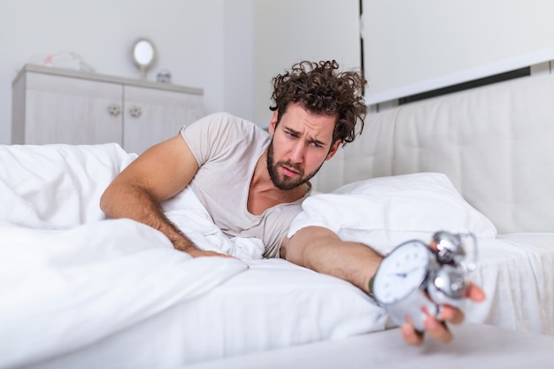 Foto odio questo rumore. problema con il risveglio mattutino. svegliarsi presto. uomo barbuto hipster assonnato viso svegliarsi. programma giornaliero per uno stile di vita sano. sveglia che suona.