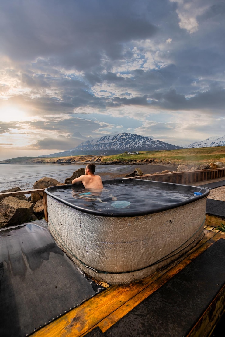 Photo hauganes geothermal hot tubs with a view of icelandic mountains and coastline