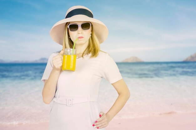 Haughty woman enjoying orange juice on beach