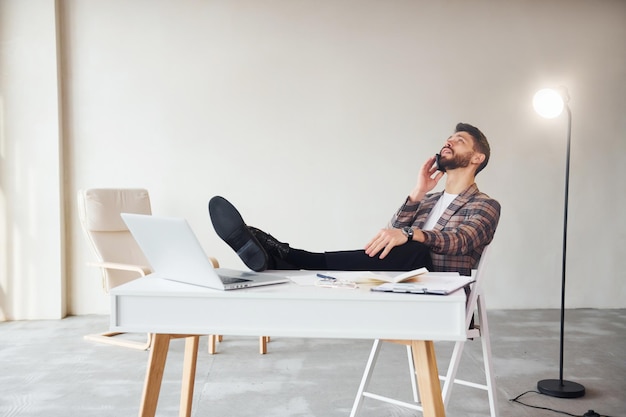 Have conversation by phone Young stylish businessman in suit indoors Conception of success