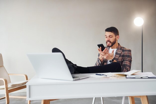 Have conversation by phone Young stylish businessman in suit indoors Conception of success