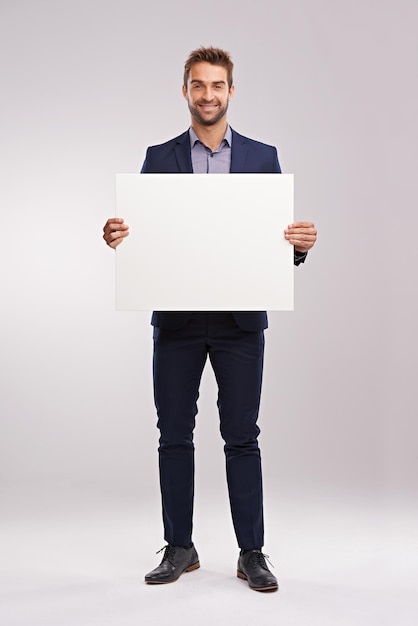 Have I got news for you Studio shot of a handsome man in a suit holding up a blank sign